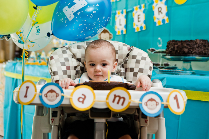 Baby in high chair with his first birthday cake