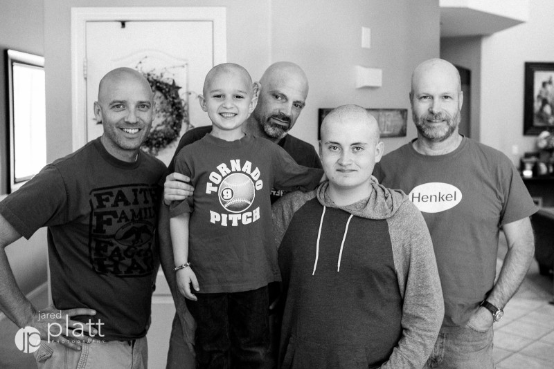 group of men with shaved heads supporting a young child in his battle against cancer