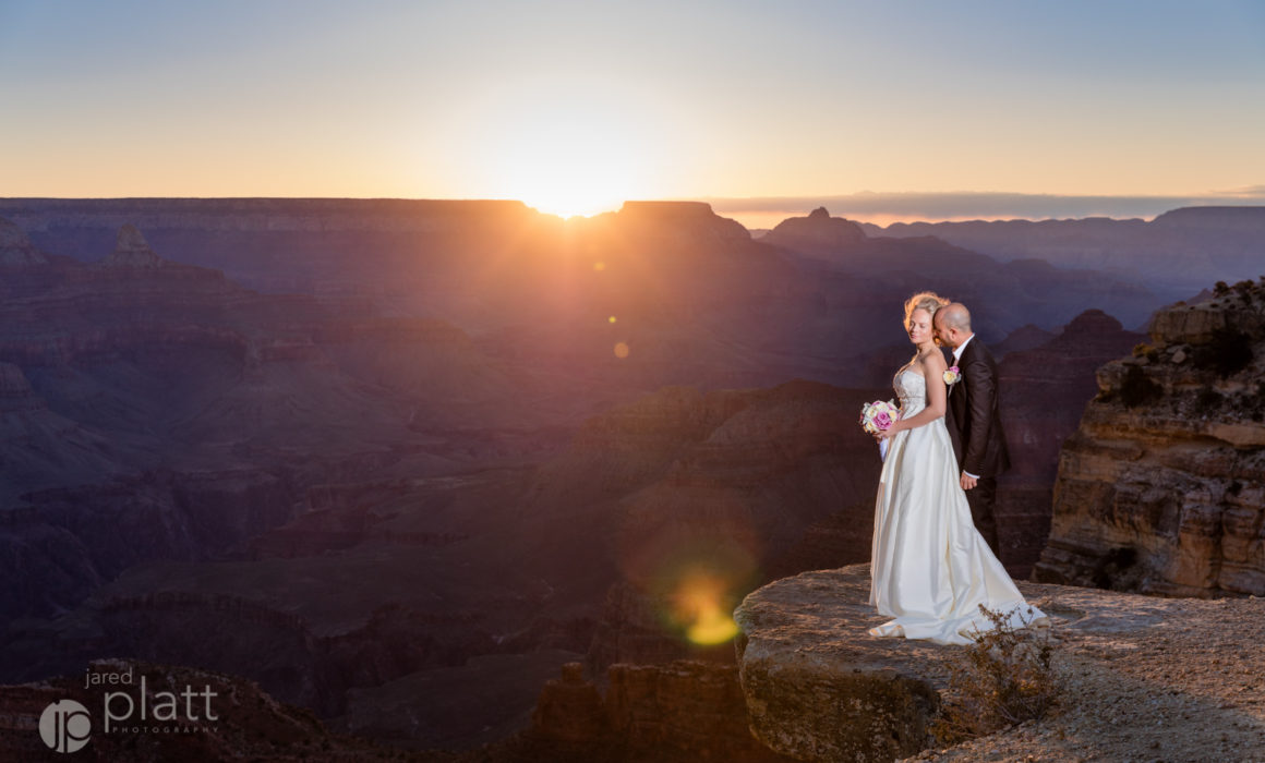 Bride and groom on the edge of the grand canyon at sunrise.