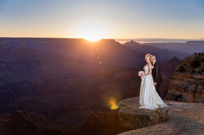 Bride and groom on the edge of the grand canyon at sunrise
