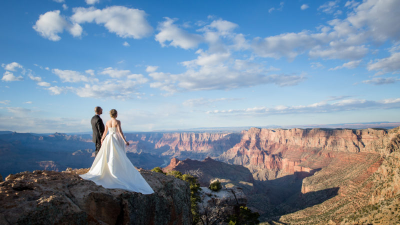 bride and groom on a cliff overlooking the grand canyon on their destination wedding elopement